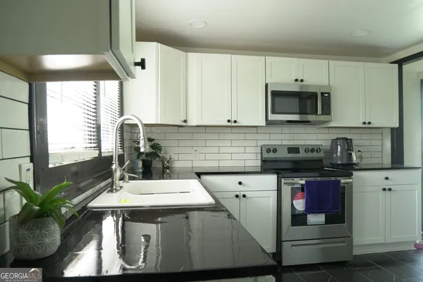 a kitchen with stainless steel appliances a sink a stove a microwave a sink and cabinets