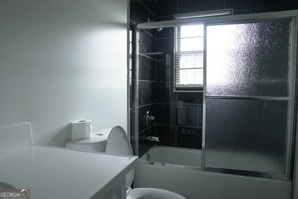 a bedroom with a bed a flat screen tv and a window