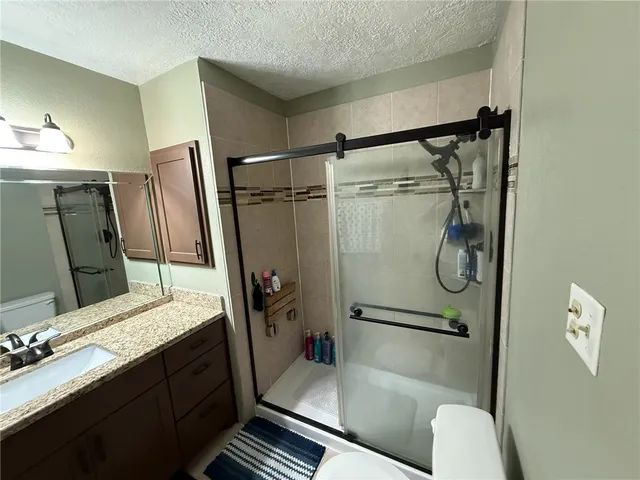 a bathroom with a granite countertop sink toilet and shower