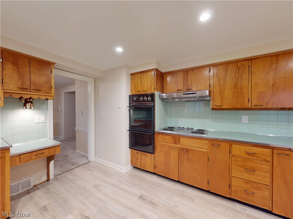 145 Overlook Road Painesville, OH 44077 - Photo 23 of 36 Kitchen featuring decorative backsplash, wood finish cabinetry, light countertops, light wood finished floors, and stainless steel electric cooktop