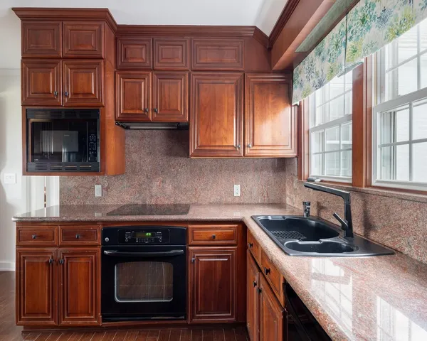 a kitchen with granite countertop a stove sink and cabinets