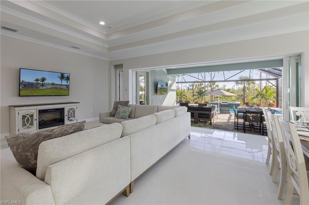 8982 Gustavia Court Naples, FL 34113 - Photo 5 of 44 a living room with furniture a fireplace and a floor to ceiling window
