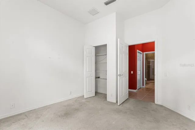 an empty room with windows and chandelier fan
