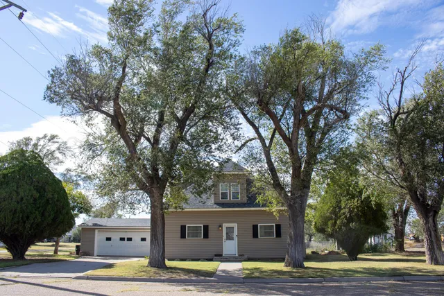 a front view of a house with a garden and tree