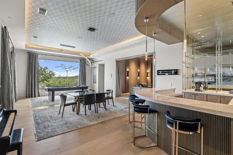 a dining hall with stainless steel appliances granite countertop a stove a sink a dining table and chairs with wooden floor