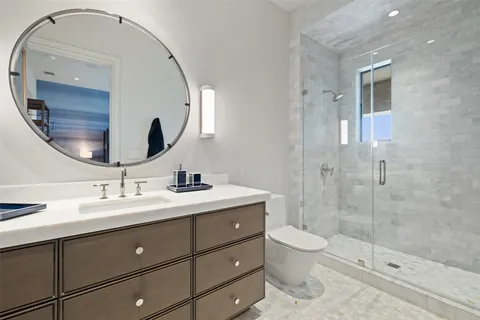 a bathroom with a double vanity sink toilet mirror and shower