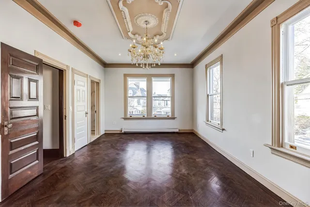 wooden floor in an empty room with a chandelier