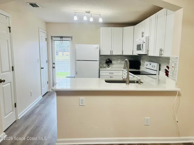 a kitchen with kitchen island a sink a stove a refrigerator and white cabinets
