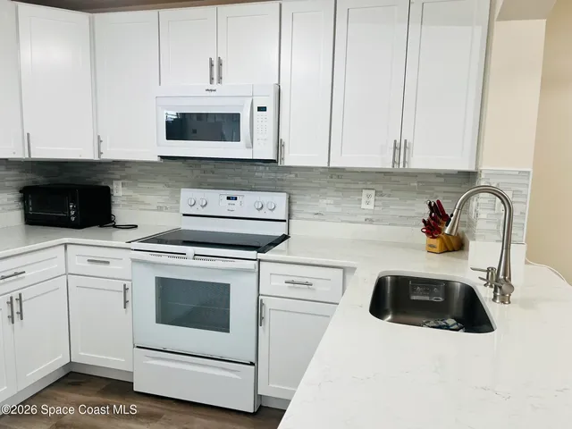 a kitchen with granite countertop white cabinets and white appliances