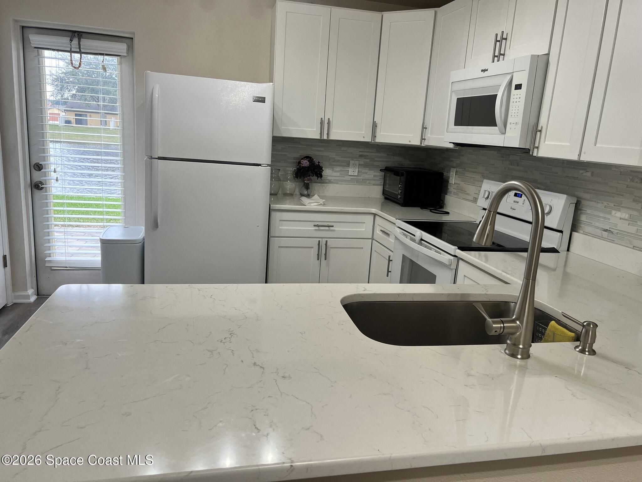 1145 Luminary Circle, Unit 104 Melbourne, FL 32901 - Photo 10 of 37 a kitchen with a refrigerator and a sink
