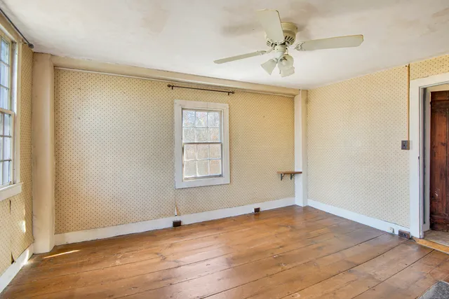 an empty room with windows and a fireplace