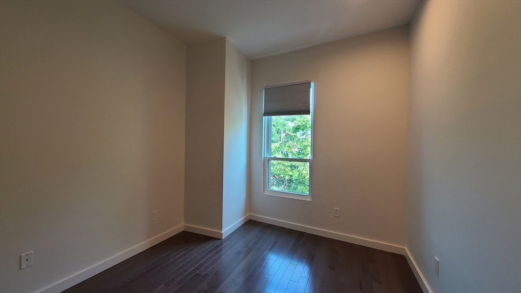 143-171 Hyde Park Avenue, Unit 163B Boston, MA 02130 - Photo 17 of 24 a view of an empty room with wooden floor and a window
