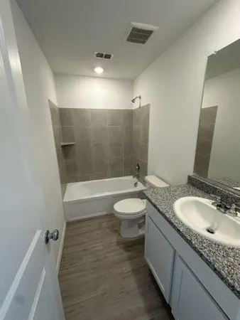 a bathroom with a granite countertop sink a mirror and a toilet