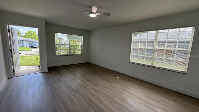 a view of an empty room with wooden floor and a window