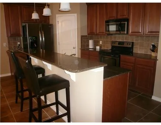 a kitchen with stainless steel appliances granite countertop a refrigerator a stove top oven and a sink