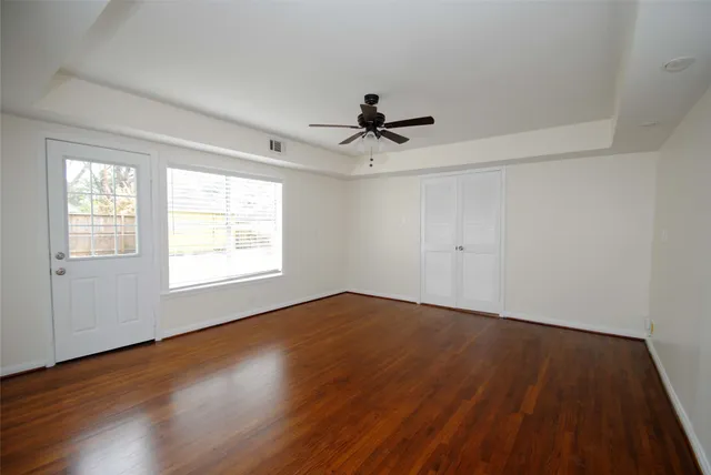 an empty room with wooden floor and windows