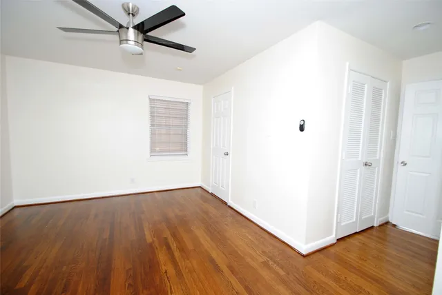 an empty room with wooden floor closet and windows