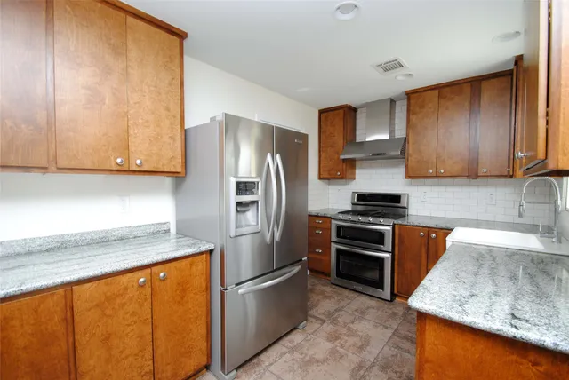 a kitchen with stainless steel appliances granite countertop a refrigerator stove and sink