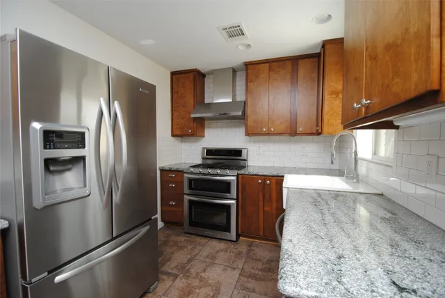 a kitchen with stainless steel appliances granite countertop a refrigerator and a stove