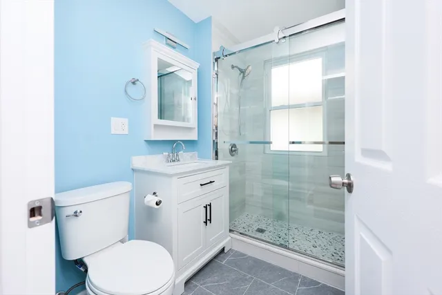 a bathroom with a granite countertop toilet a sink and a mirror