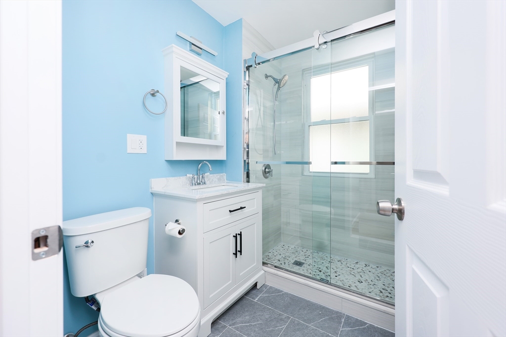 15-17 Saunders Street, Unit 15 Boston, MA 02134 - Photo 11 of 22 a bathroom with a granite countertop toilet a sink and a mirror
