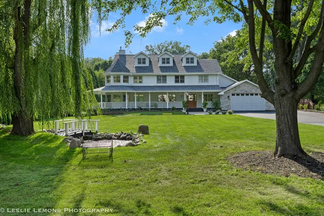 an aerial view of a house with outdoor space lake and trees all around