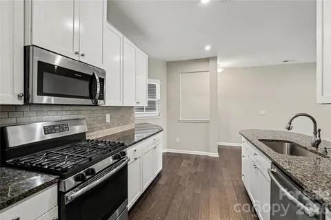 a kitchen with granite countertop a sink and steel appliances