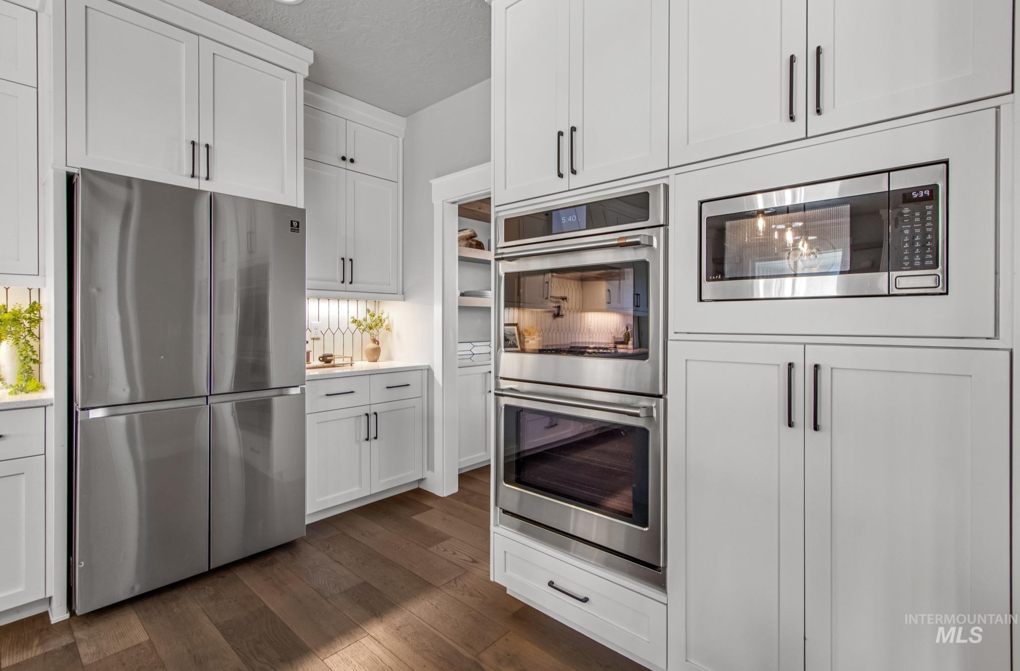 25427 Havard Oak Place Caldwell, ID 83607 - Photo 19 of 50 Kitchen with stainless steel appliances, a textured ceiling, white cabinets, and dark wood-style floors