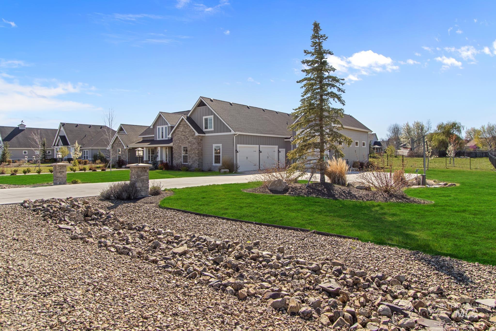 25427 Havard Oak Place Caldwell, ID 83607 - Photo 3 of 50 View of front of house with stone siding, concrete driveway, a residential view, and a garage