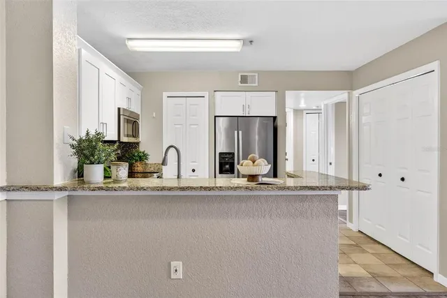 a white kitchen with granite countertop a sink and white cabinets