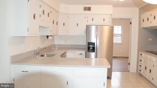 a kitchen with stainless steel appliances granite countertop a refrigerator a sink and white cabinets
