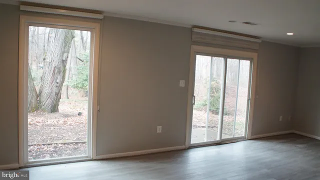 a view of an empty room and wooden floor and a window