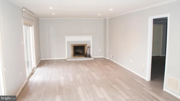 an empty room with wooden floor fireplace and windows