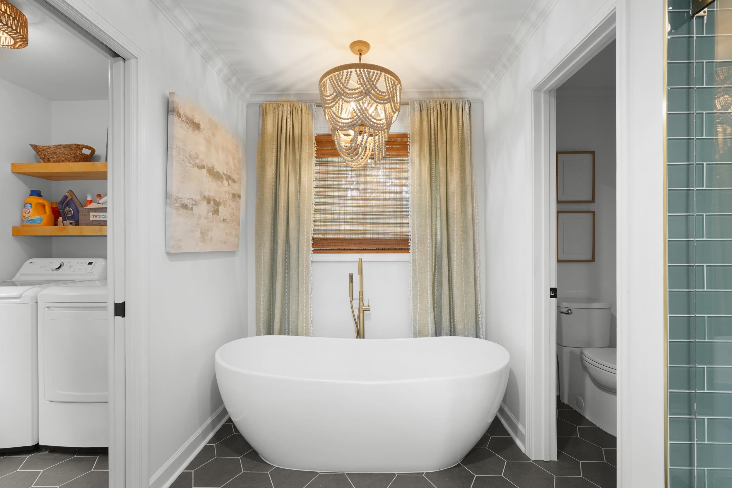 55 Blueberry Road Eads, TN 38028 - Photo 24 of 40 Full bath featuring independent washer and dryer, a chandelier, a freestanding tub, and tile patterned floors