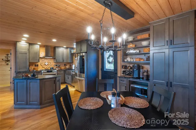 a kitchen with stainless steel appliances kitchen island granite countertop a refrigerator a stove a sink and a dining table with wooden floor