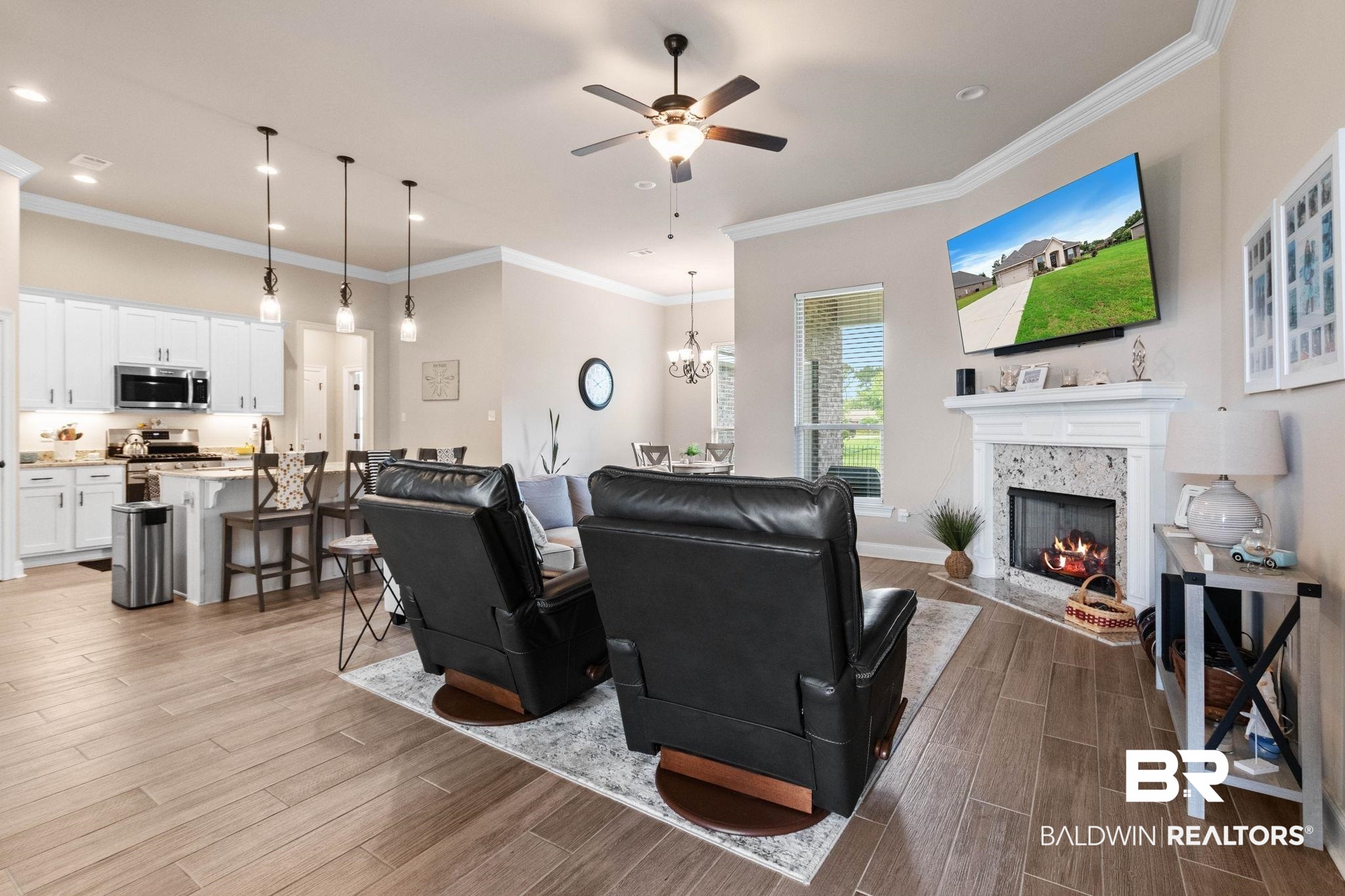 22244 Hibiscus Circle Foley, AL 36535 - Photo 14 of 51 Open-concept living space featuring wood-finish flooring, a contemporary fireplace with a stone surround, and crown molding
