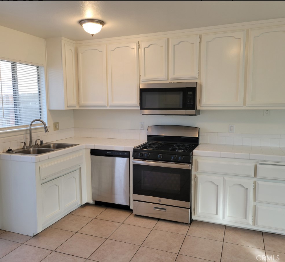 16140 Tawney Ridge Lane, Unit B Victorville, CA 92394 - Photo 4 of 12 a kitchen with white cabinets stainless steel appliances and sink