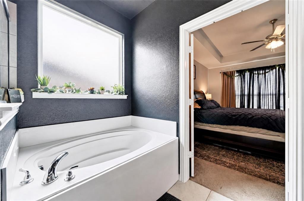 113 Ridgetop Trail Rhome, TX 76078 - Photo 23 of 32 Built-in soaking tub with chrome fixtures, large frosted window, and a recessed ceiling fan in the adjacent room