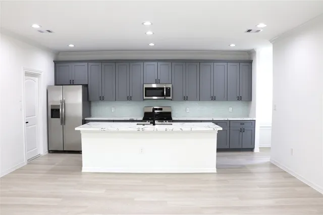 a kitchen with stainless steel appliances granite countertop a stove top oven a refrigerator a sink and a microwave