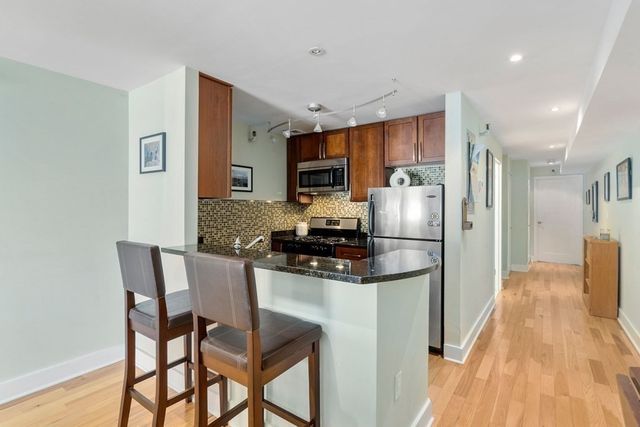 a kitchen with stainless steel appliances granite countertop a dining table chairs refrigerator and sink
