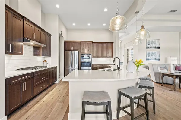 a large kitchen with kitchen island a large counter space a sink appliances and a large window