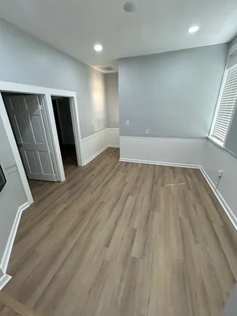 an empty room with wooden floor and windows