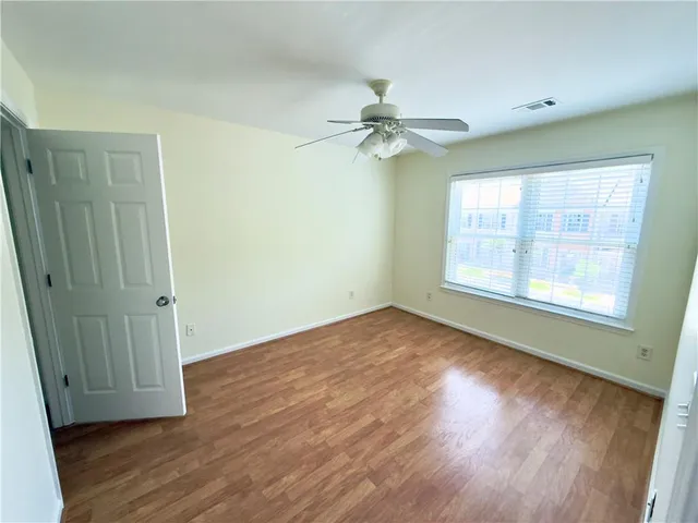 an empty room with wooden floor fan and windows