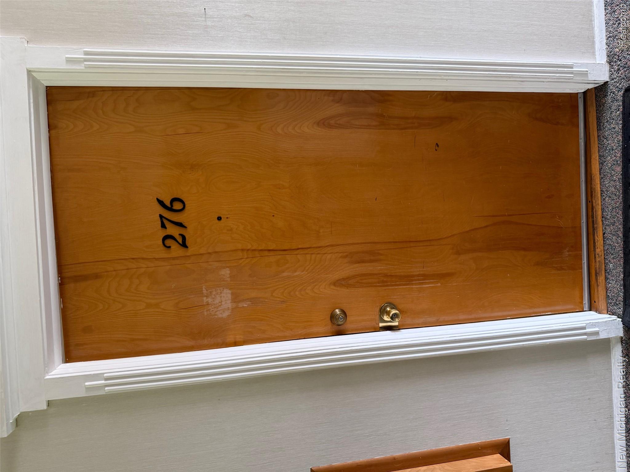 29276 Hoover Road, Unit 276 Warren, MI 48093 - Photo 8 of 14 Wood-finish entry door with brass hardware and white decorative trim