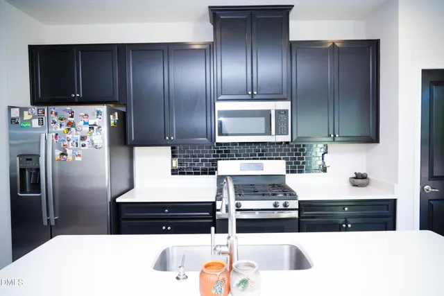 a kitchen with stainless steel appliances a kitchen island hardwood floor sink stove dining table and chairs