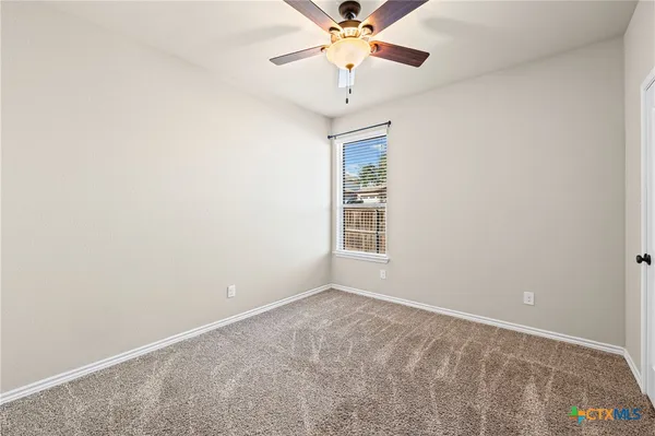 an empty room with a chandelier fan and windows