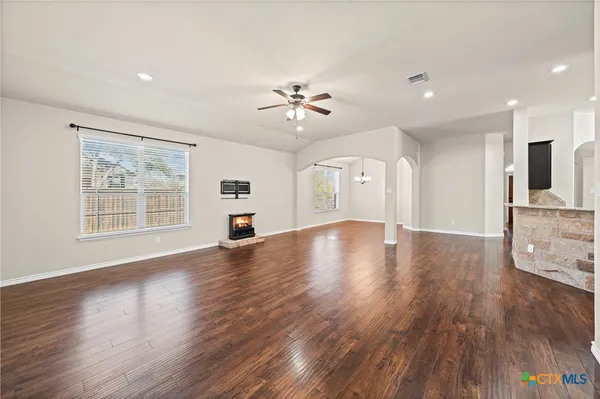 a view of an empty room with window and wooden floor
