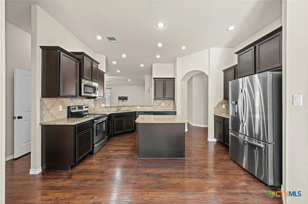 a large kitchen with stainless steel appliances a refrigerator and a stove top oven
