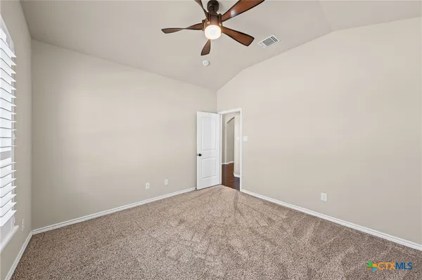 an empty room with a window and a fan