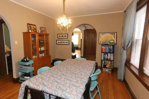 a dining room with wooden floor a chandelier a wooden table and chairs
